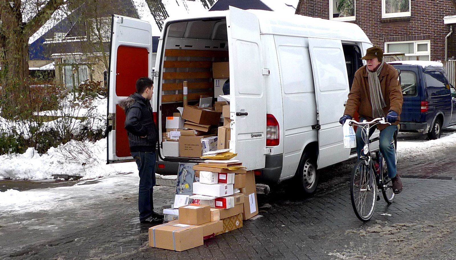 Driver looking in the back of a van with multiple boxes on the gorund